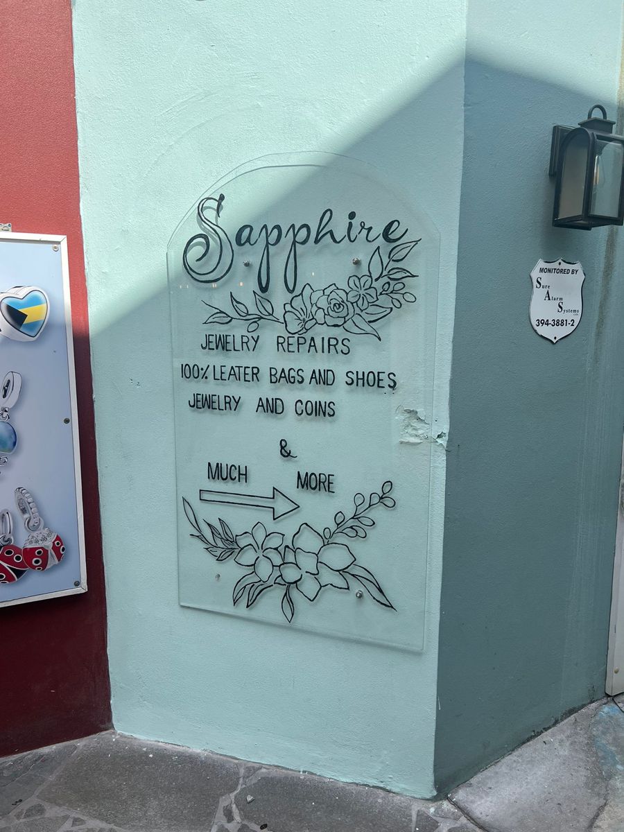 The Sapphire sign on a mint-green wall, listing jewelry repairs, leather bags and shoes, jewelry and coins
